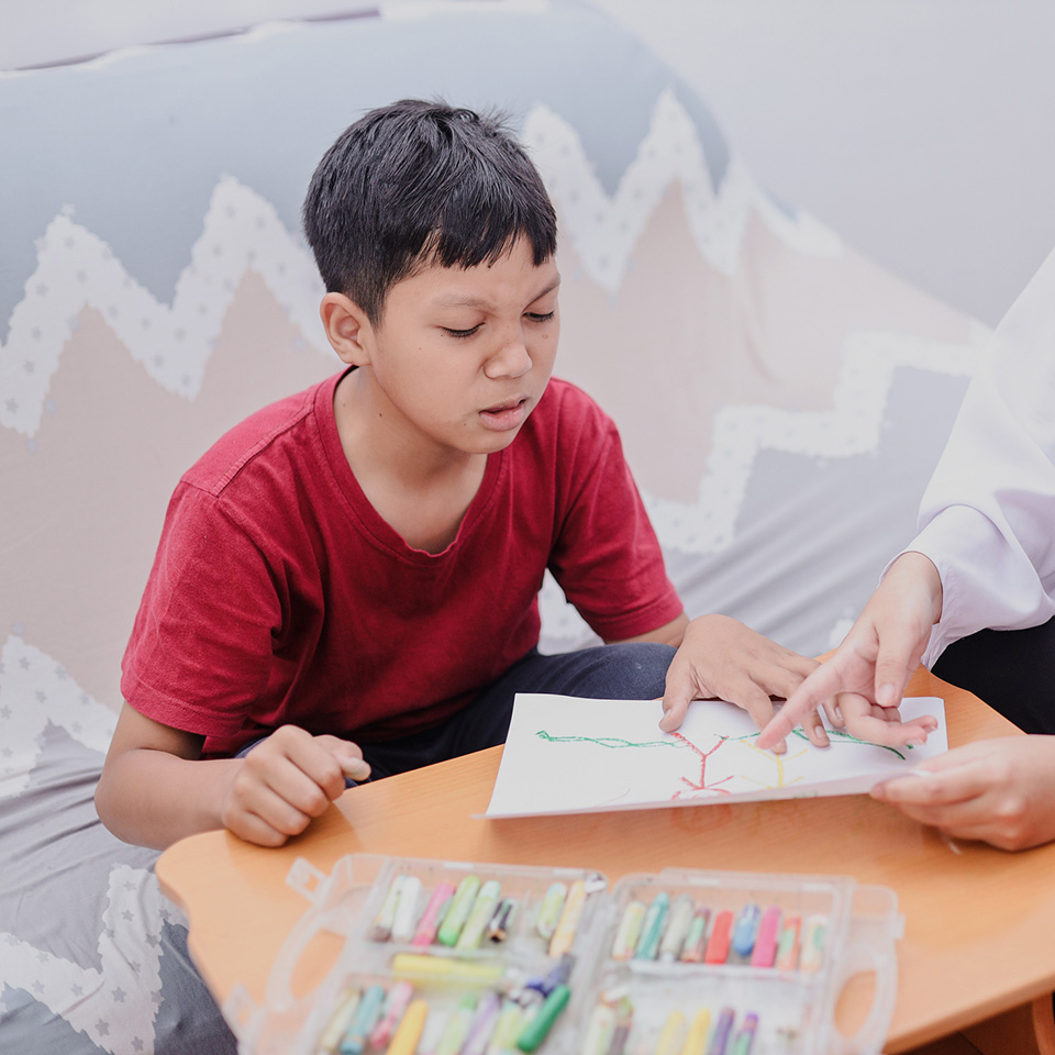 a boy sitting at a table with a drawing on it