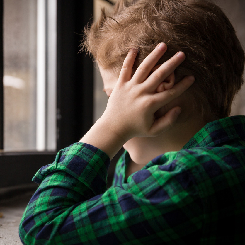 a boy with his hand on his head