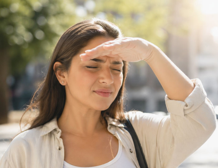 Person squinting in bright sunlight due to light sensitivity eyes